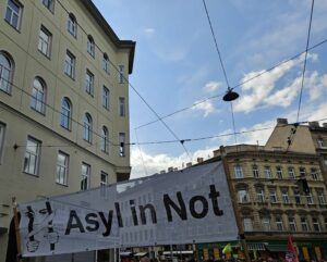 Ein weißes Banner mit der Aufschrift "Asyl in Not" auf der 1. Mai Demonstration in Wien